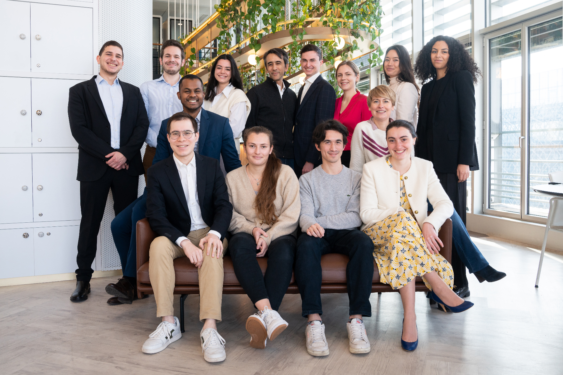 Group portrait of a team in a bright office with floor to ceiling windows