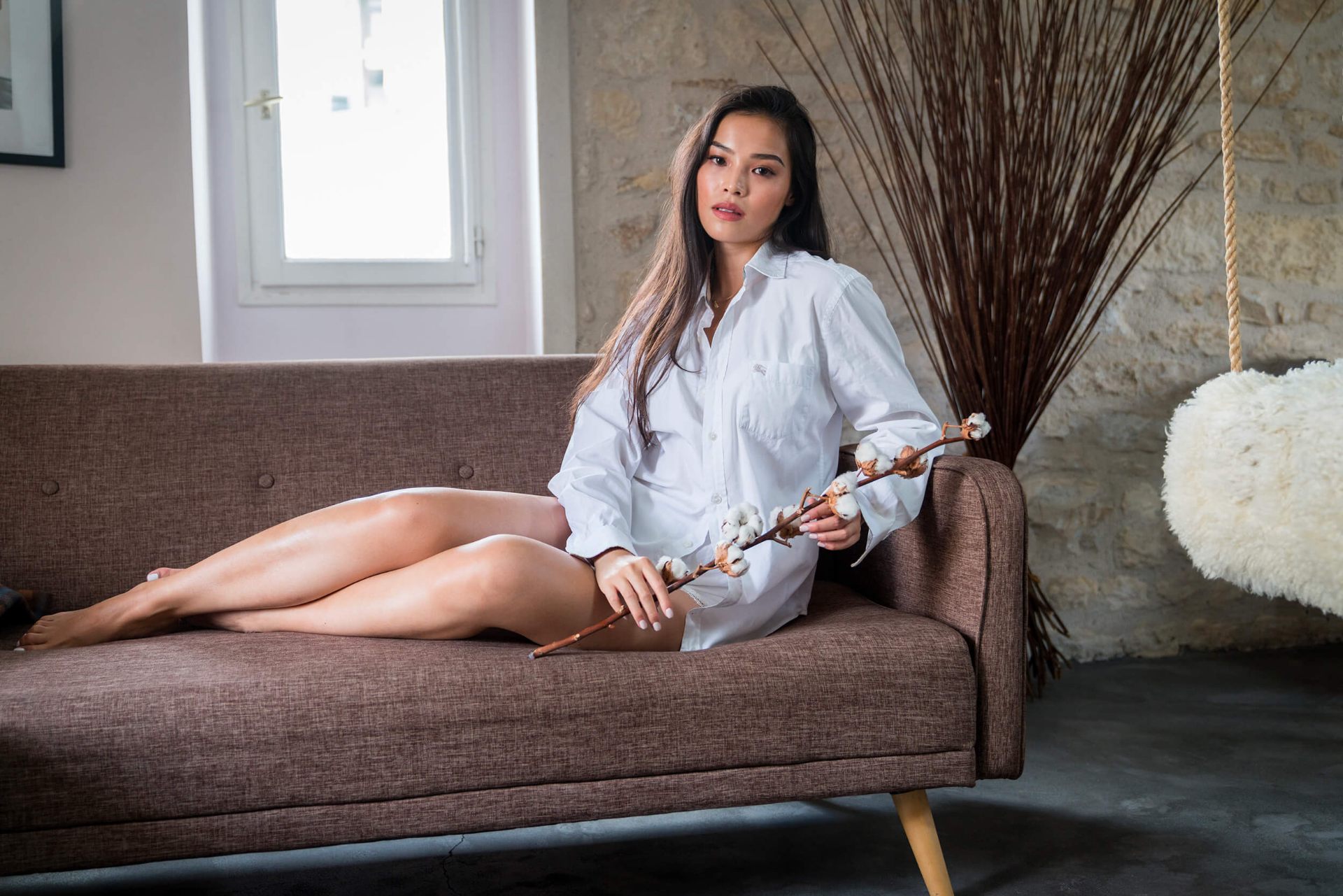 Lifestyle portrait of a woman sitting on a sofa in a bright interior